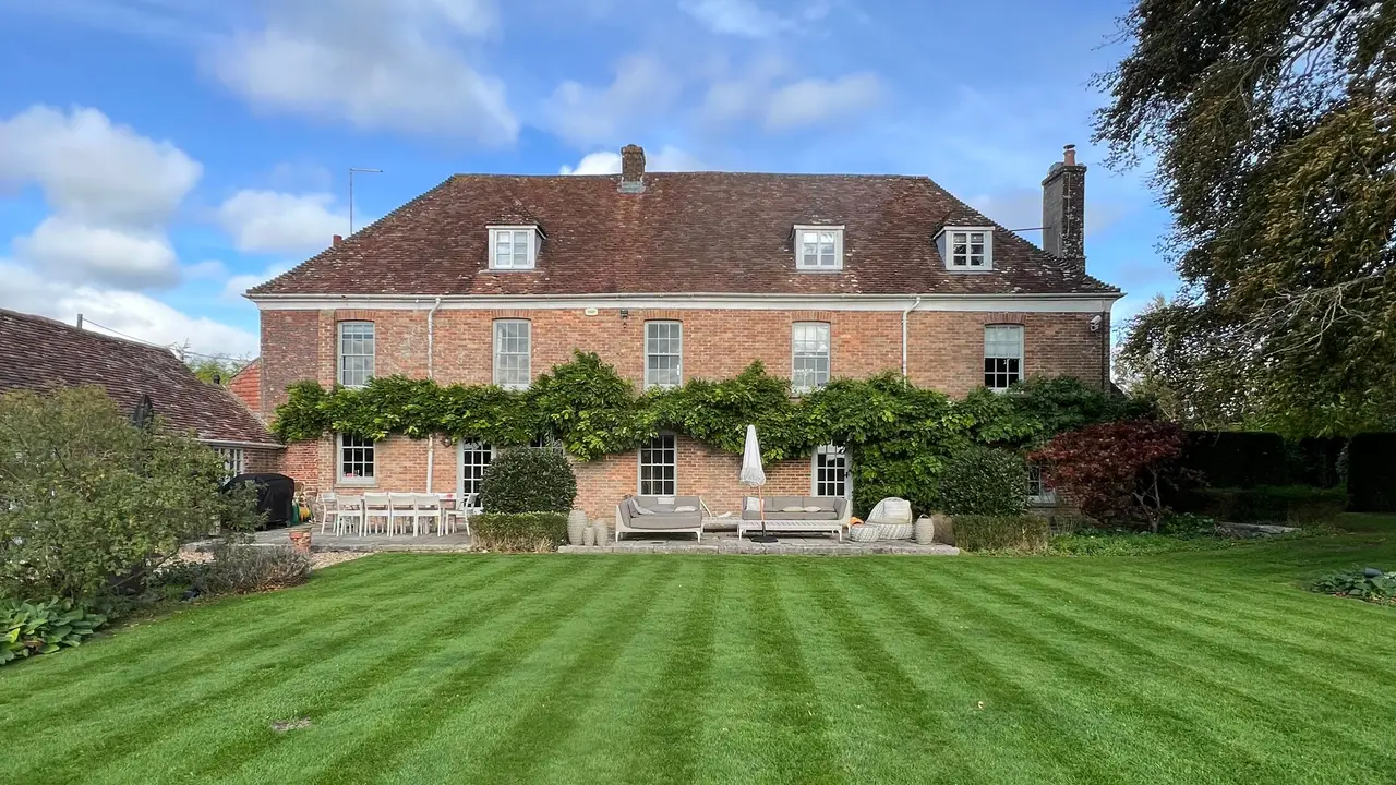 A large brick house with a freshly striped lawn